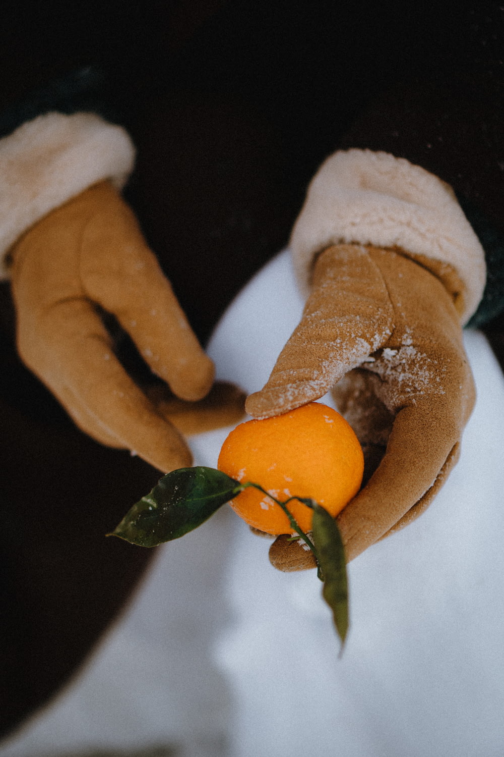 a person wearing gloves and holding an orange