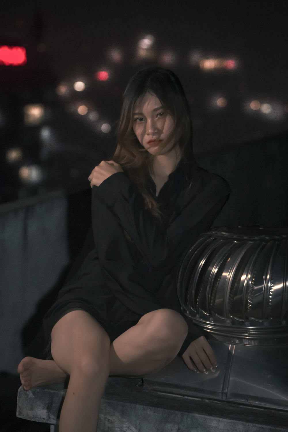 a woman in a black dress sitting on a ledge