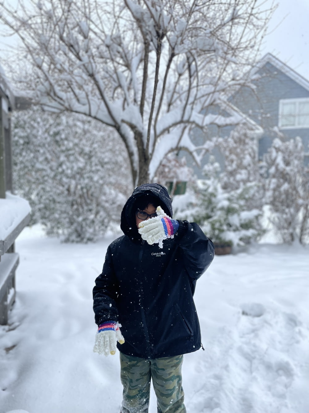 a young boy standing in the snow with his hands on his face