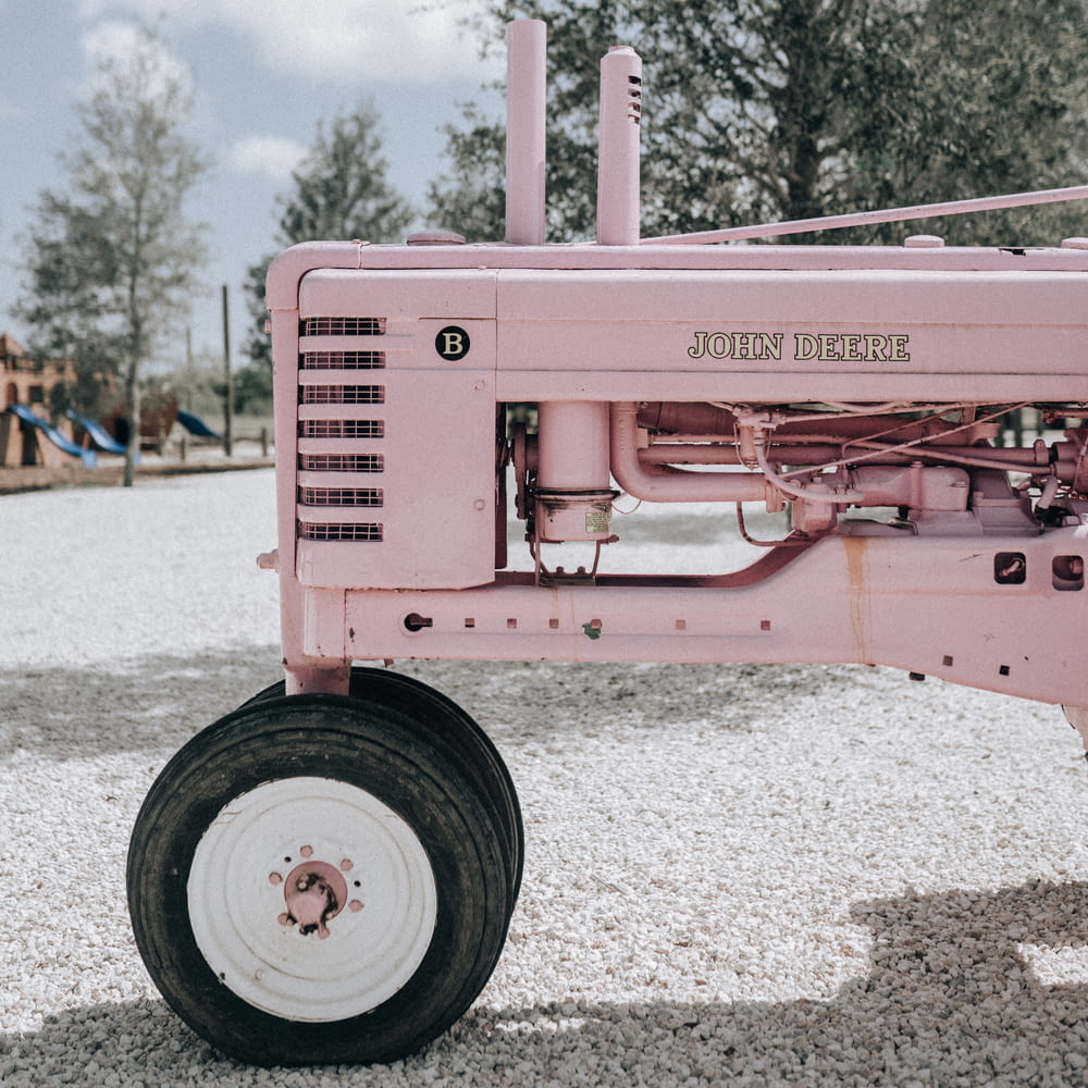 a pink tractor parked in a gravel lot