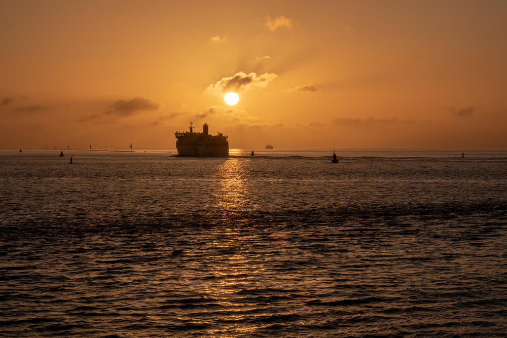 Il sole sta tramontando sull'oceano con una nave in lontananza