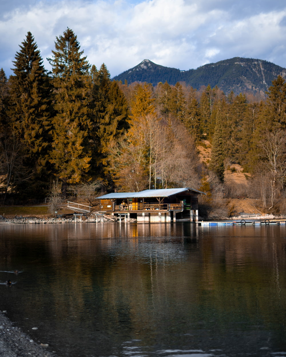a boat house on a lake with mountains in the background