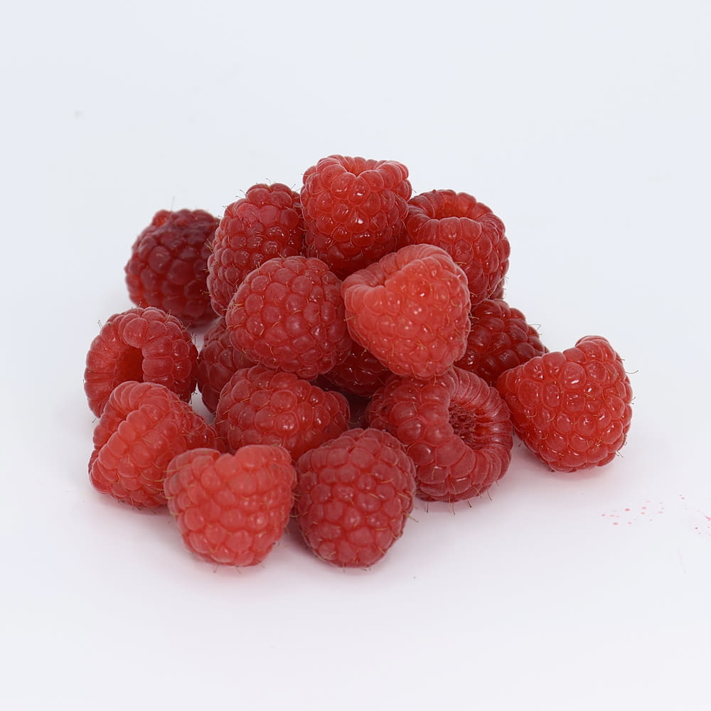 a pile of raspberries on a white background