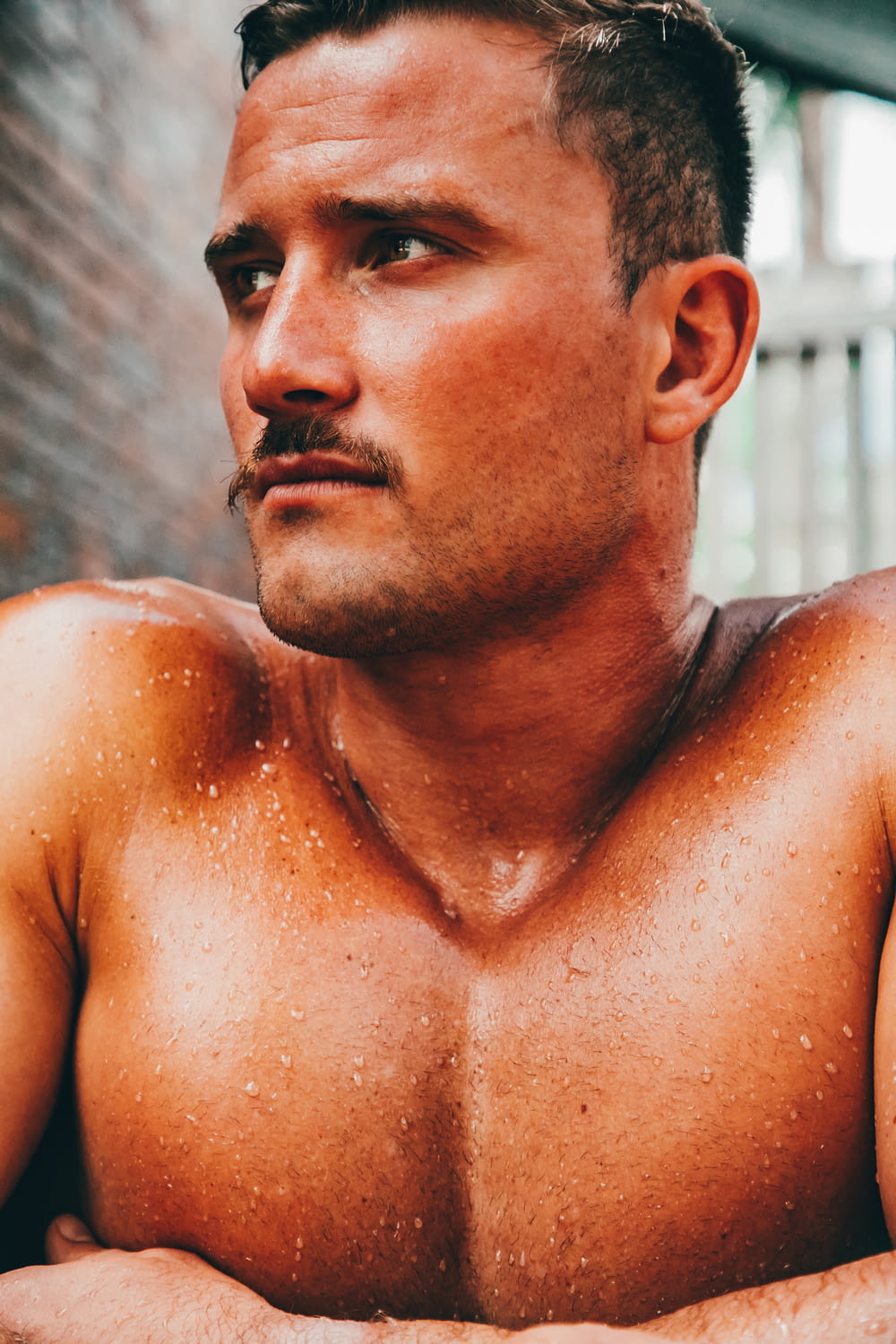 a close up of a shirtless man with his arms crossed