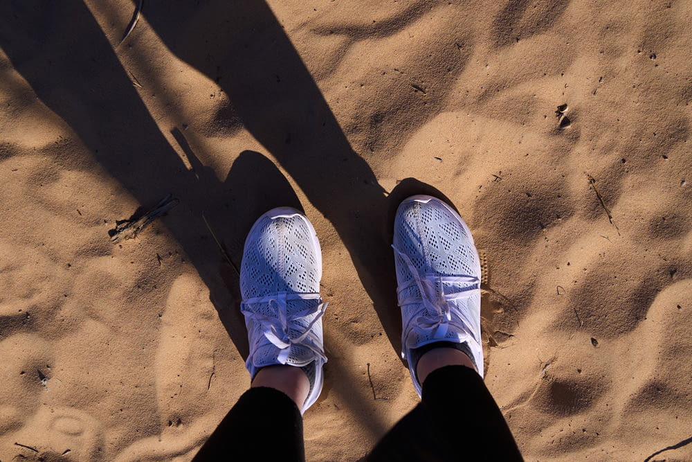 a person standing in the sand with their shoes on