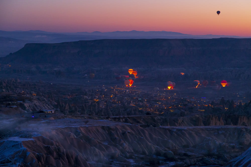 hot air balloons flying over a city at dusk