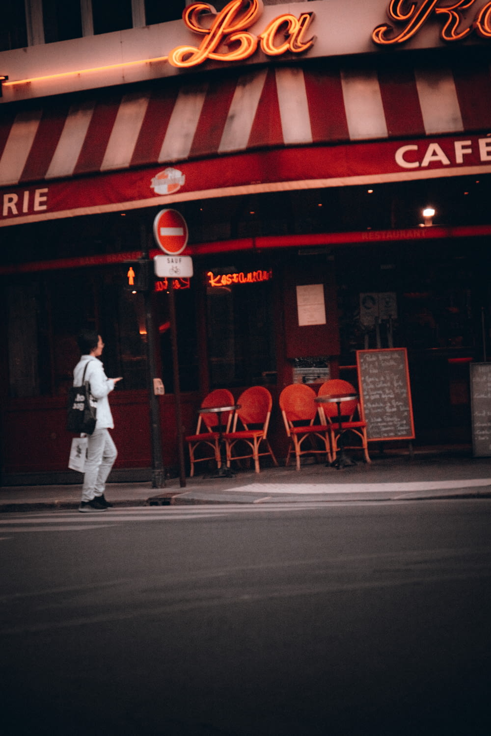 a man walking down the street in front of a cafe