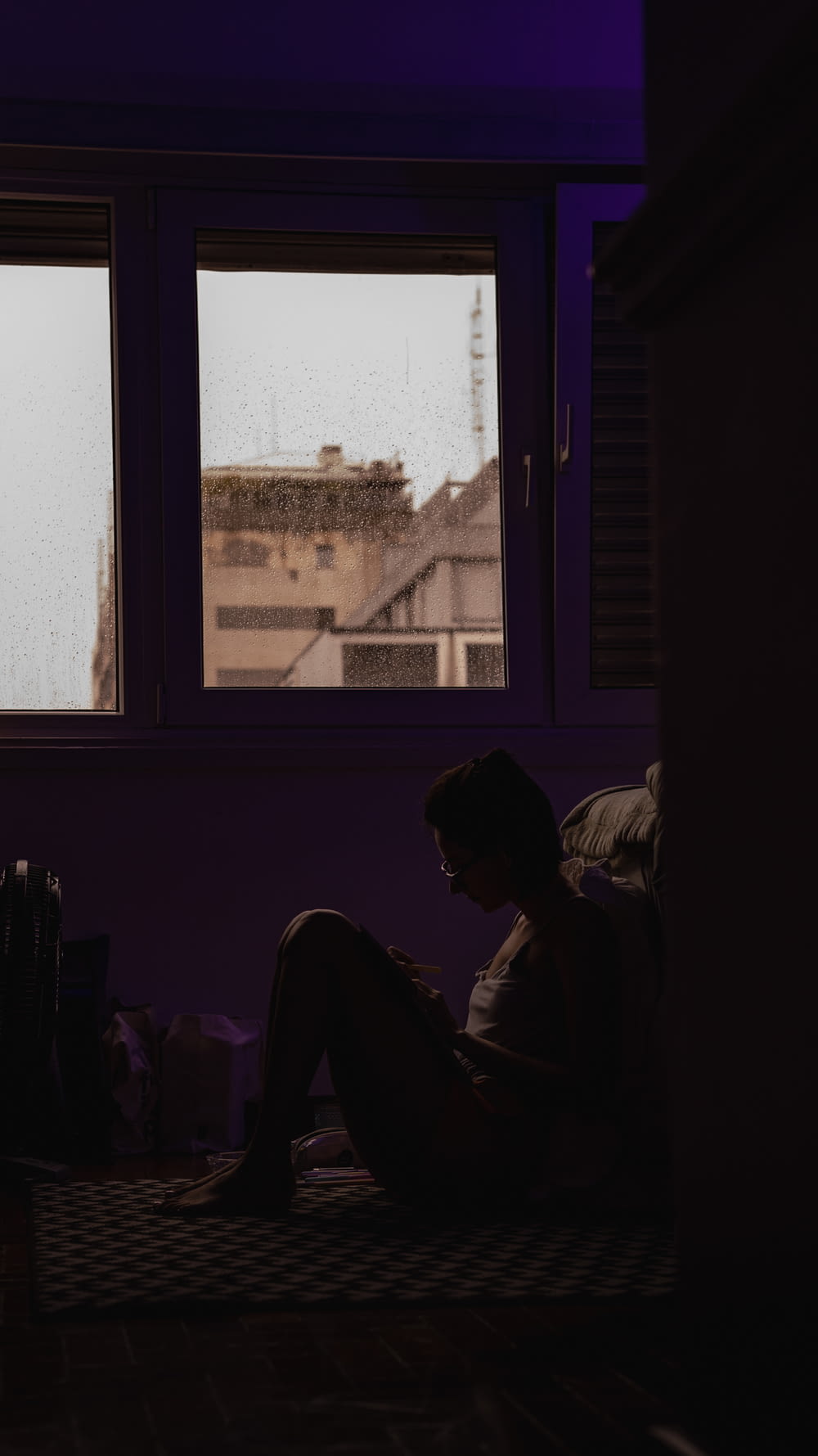a person sitting on a bed in front of a window