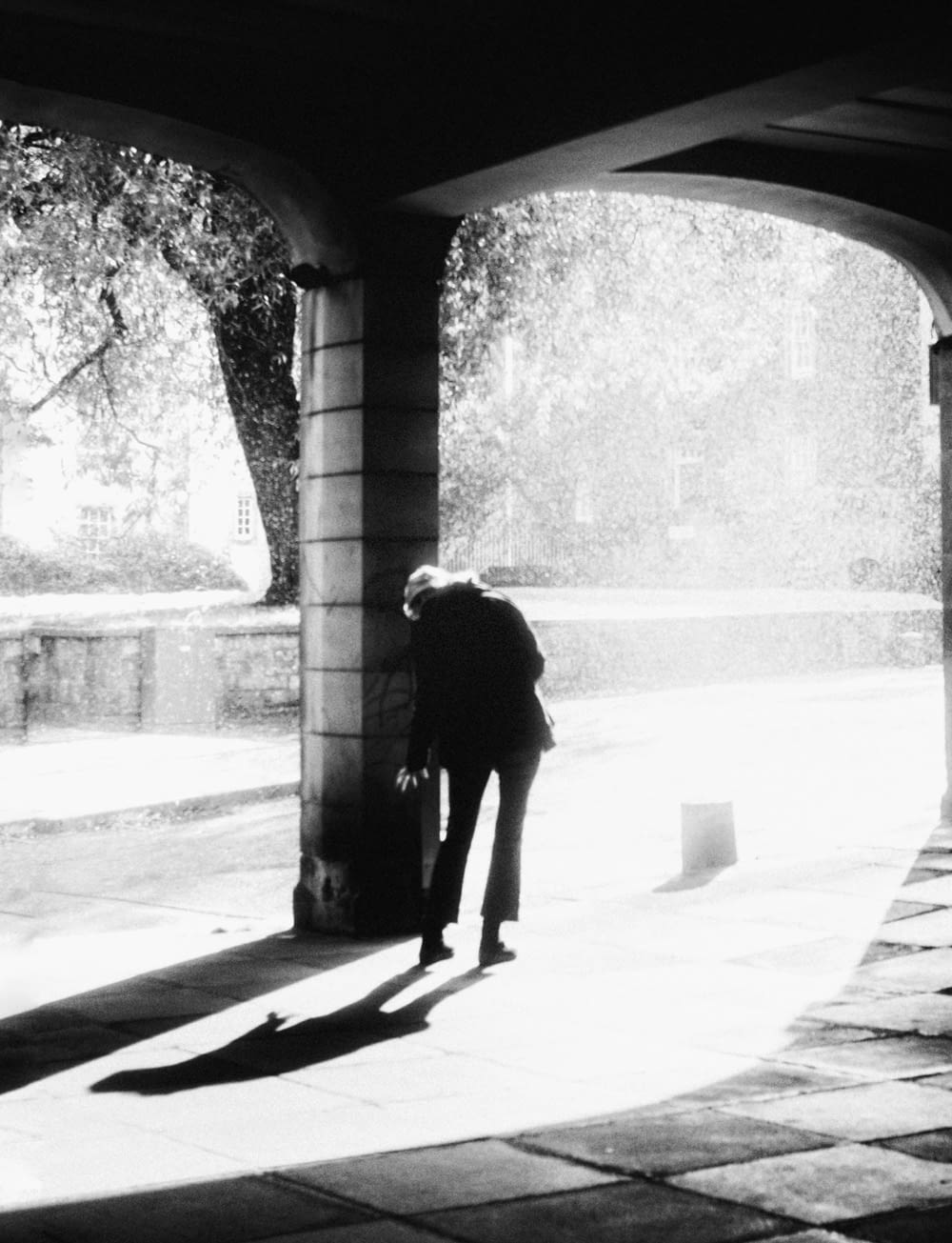 a man standing under a bridge next to a tree