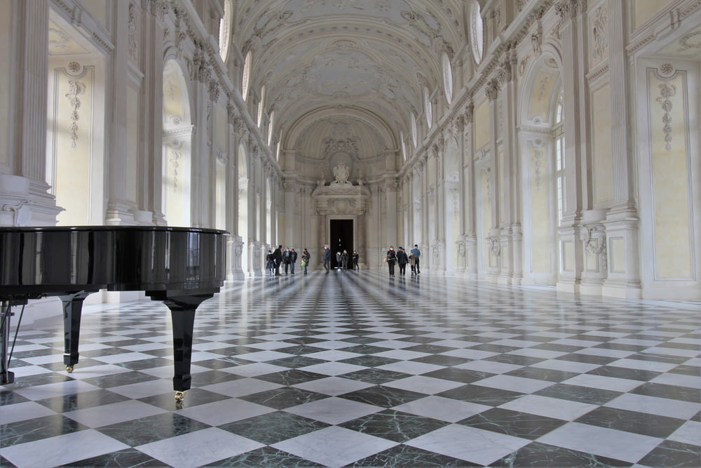 a grand piano in a large hall with a checkered floor