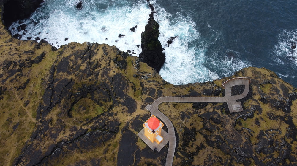 an aerial view of a lighthouse on a cliff by the ocean