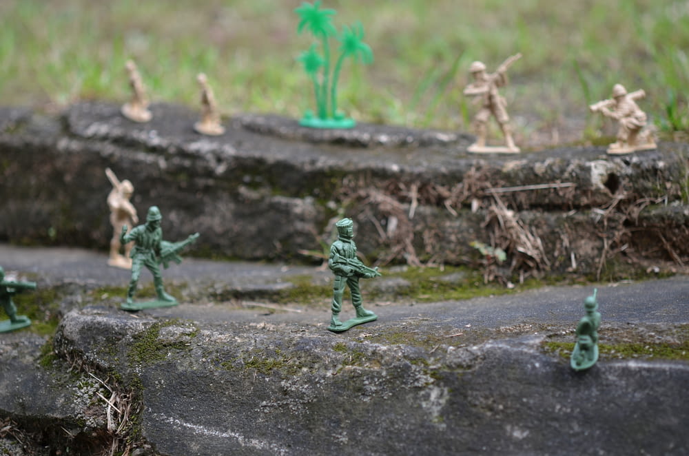 a group of toy army men standing on top of a rock