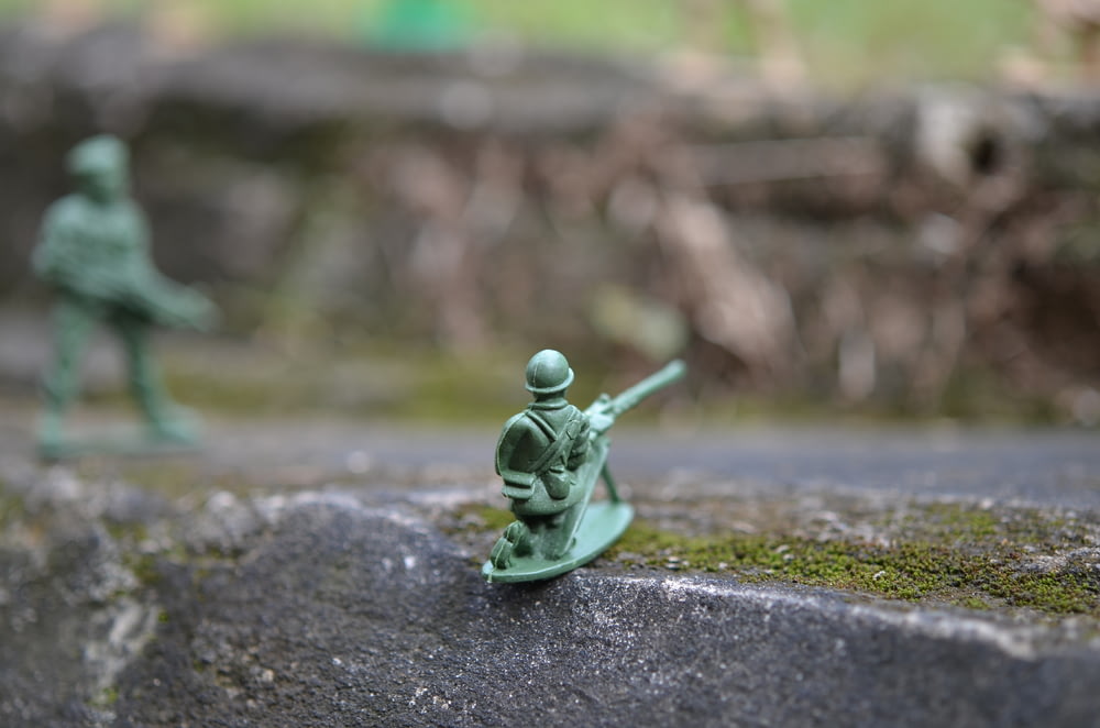a toy soldier with a gun on a rock