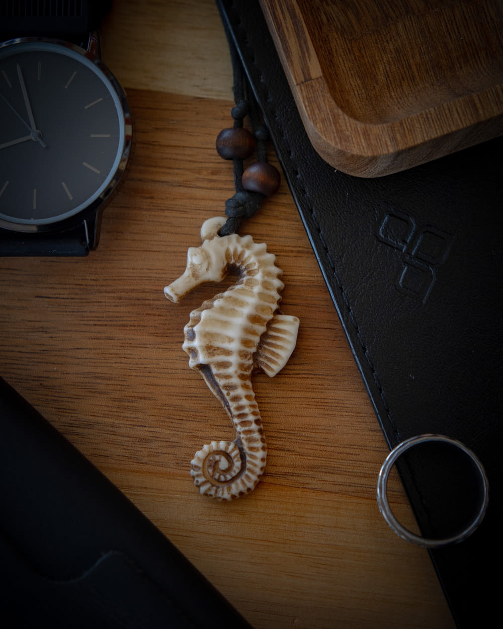 a sea horse on a wooden table next to a watch
