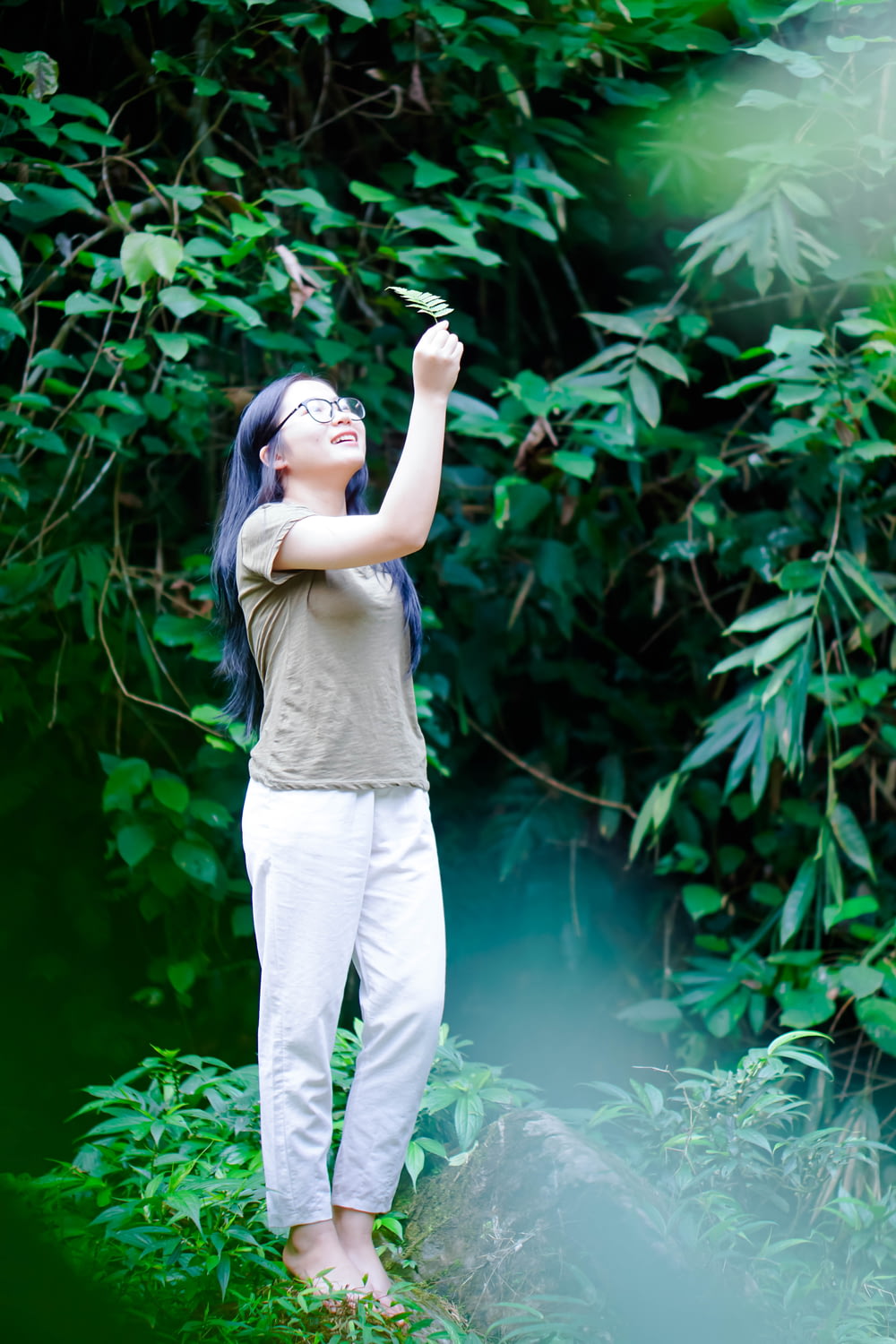 a woman standing in front of a lush green forest