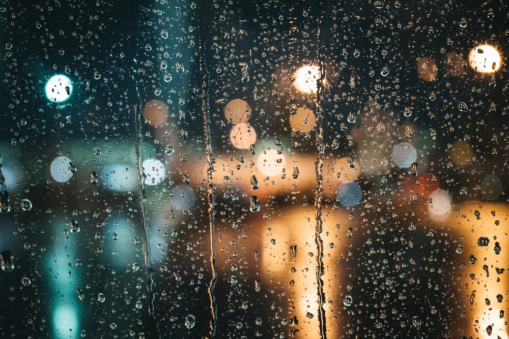 una ventana con gotas de lluvia por la noche