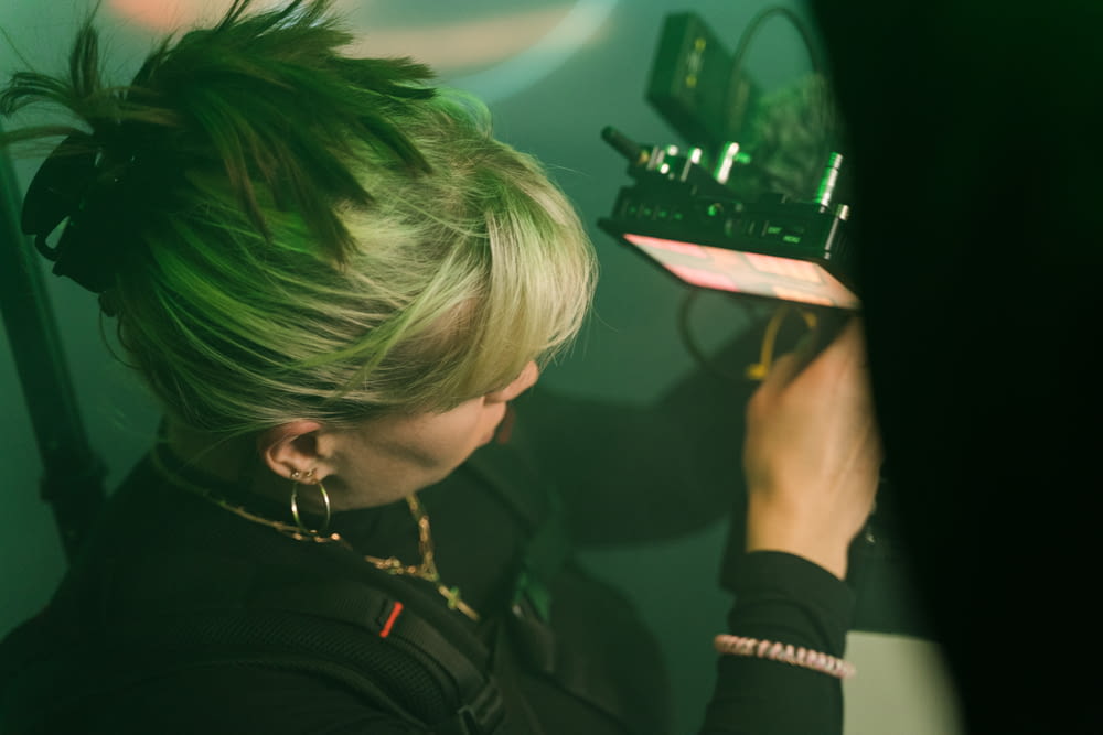Eine Frau mit grünen Haaren hält ein Radio in der Hand