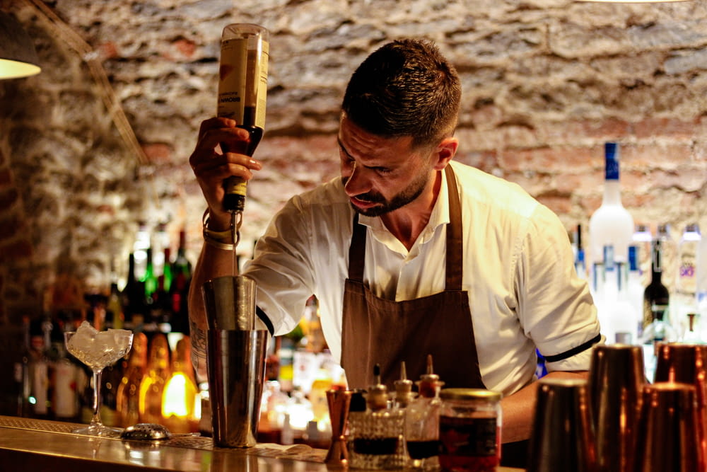 a man behind a bar making a drink