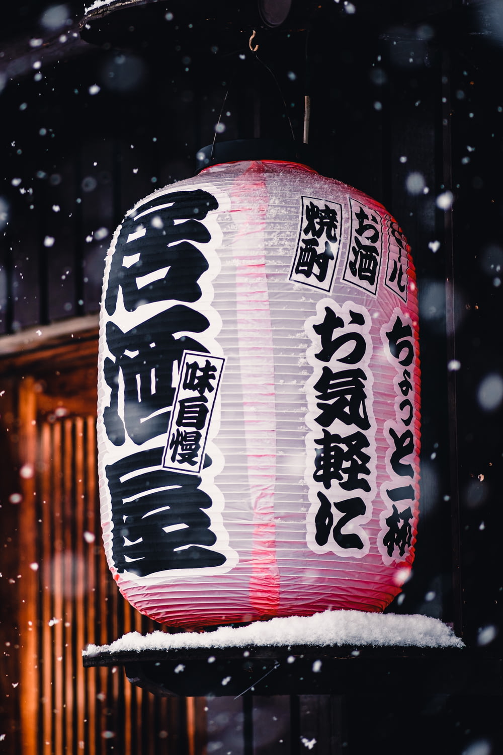 a japanese lantern hanging from a pole in the snow