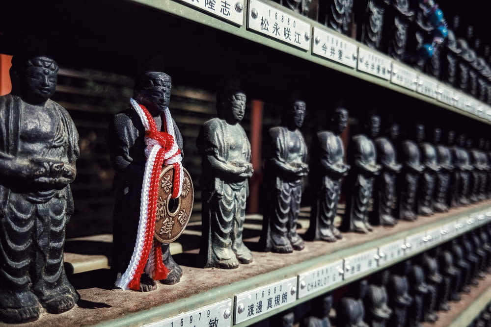 a row of buddha statues sitting on top of a shelf