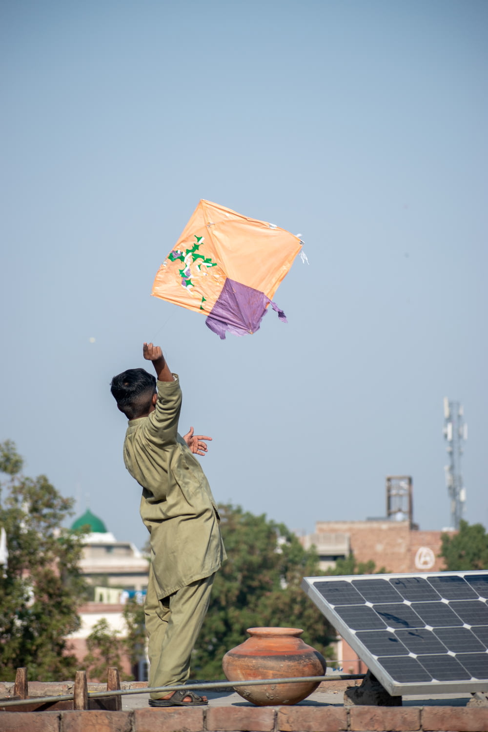 a man flying a kite on top of a roof