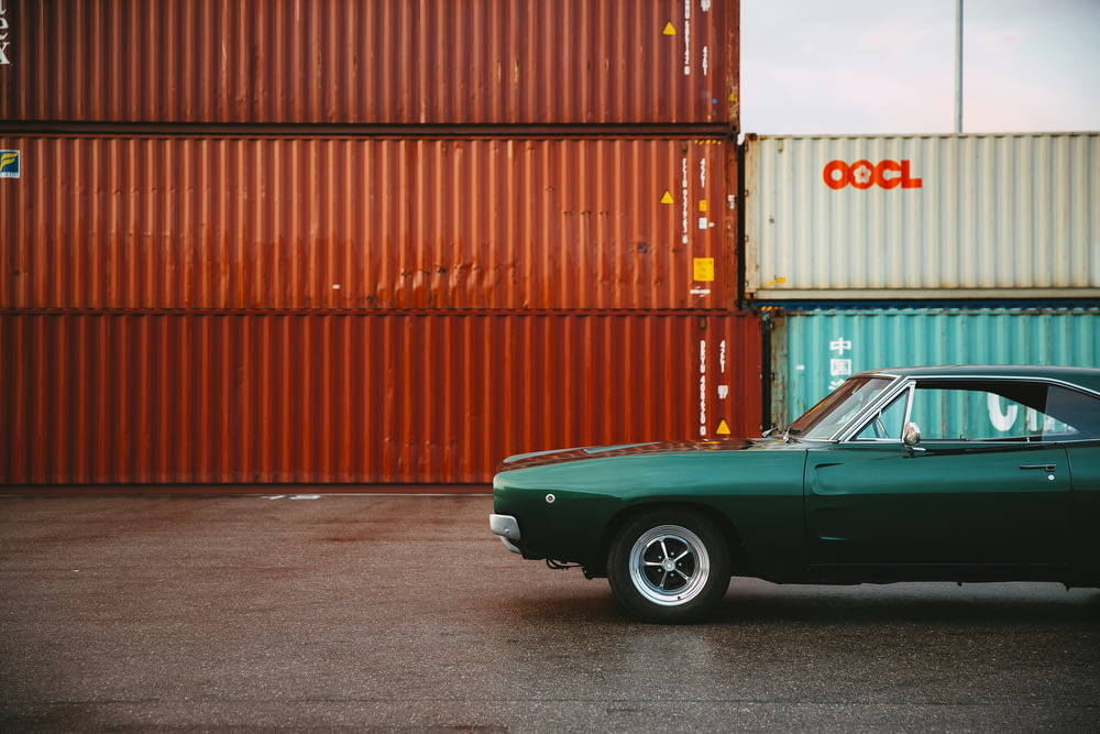 a green car parked in front of a shipping container