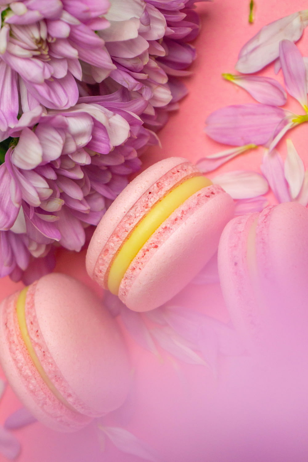 two macaroons sitting next to a bouquet of flowers