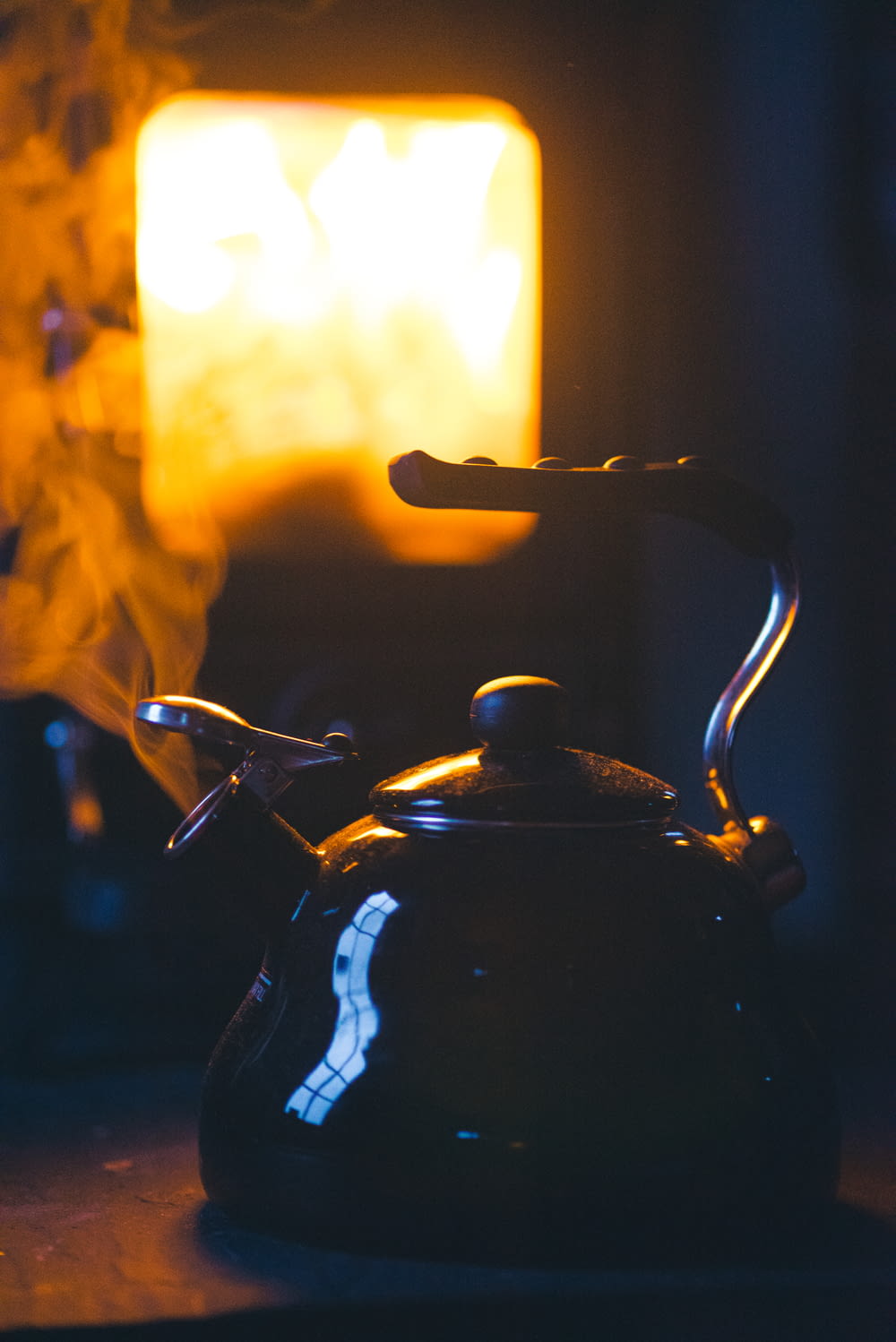 a tea kettle with a lit candle in the background