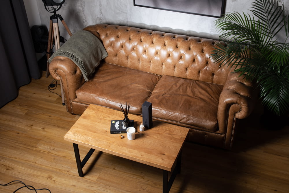 a brown leather couch sitting on top of a wooden table