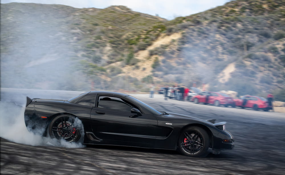 a black sports car with smoke coming out of it
