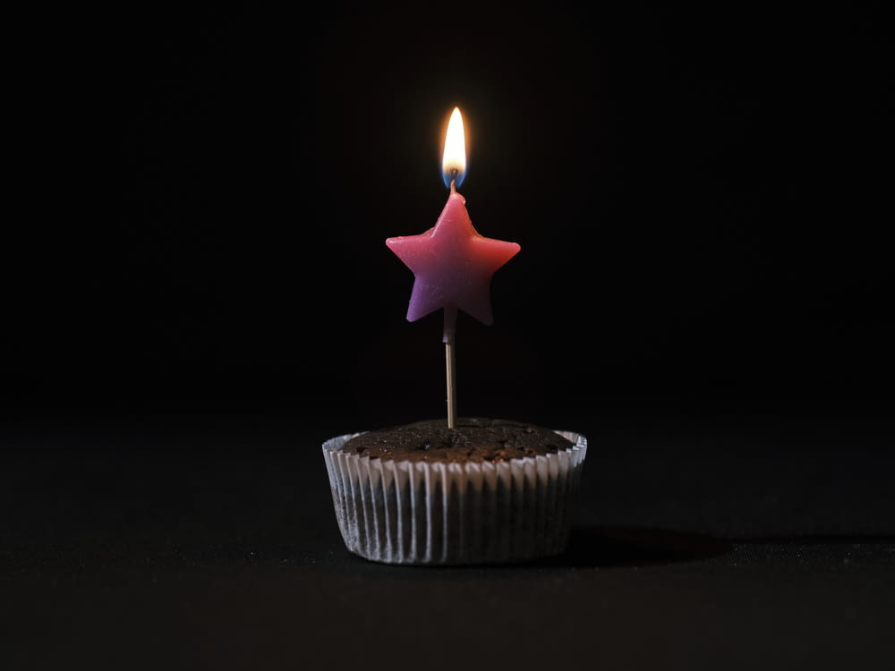 a cupcake with a lit candle sticking out of it