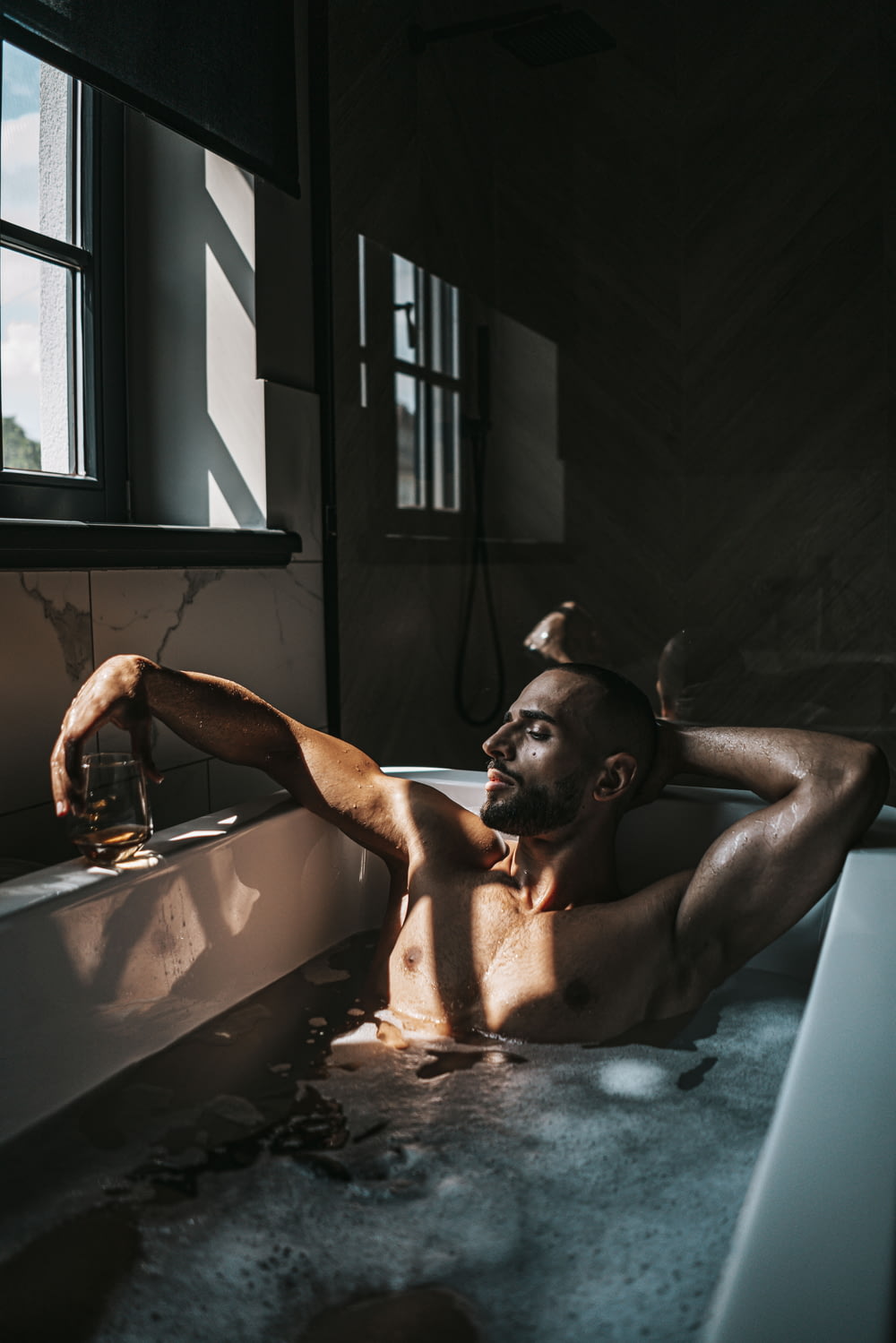 a man sitting in a bathtub with a glass of wine