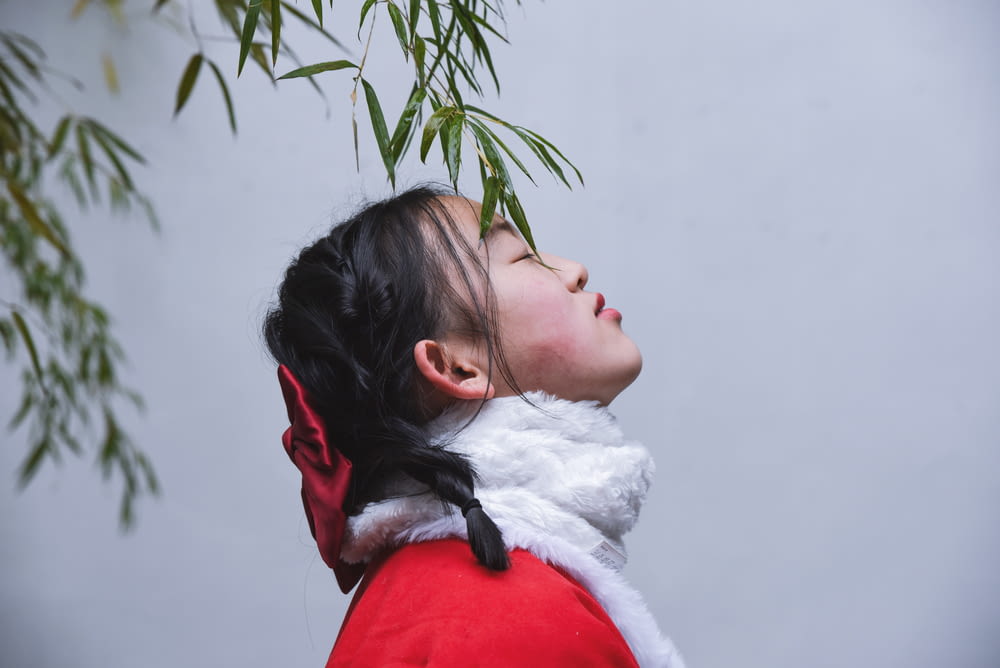 a woman in a red coat looking up at a tree
