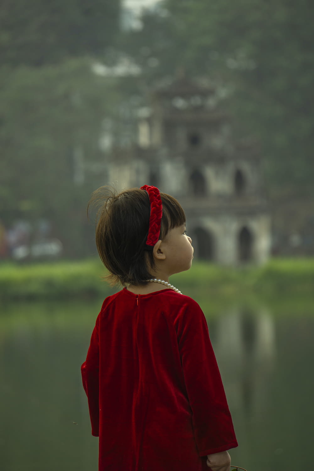 a little girl standing in front of a body of water