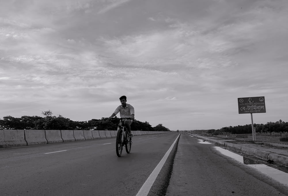um homem andando de bicicleta no meio de uma estrada