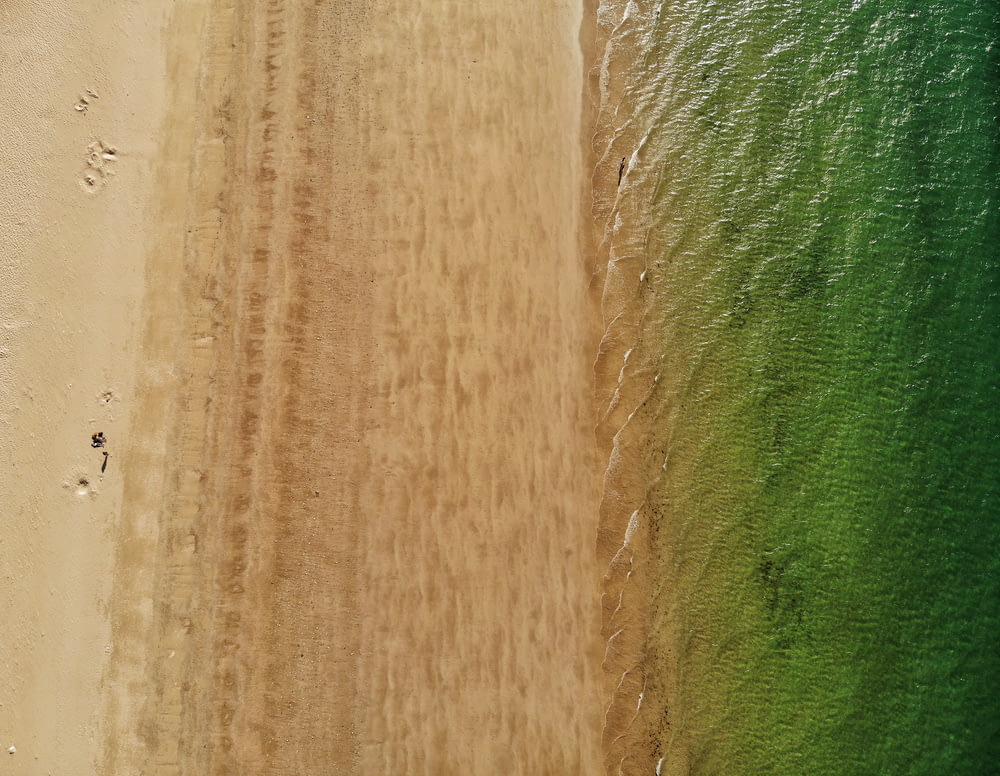 an aerial view of a sandy beach with green water