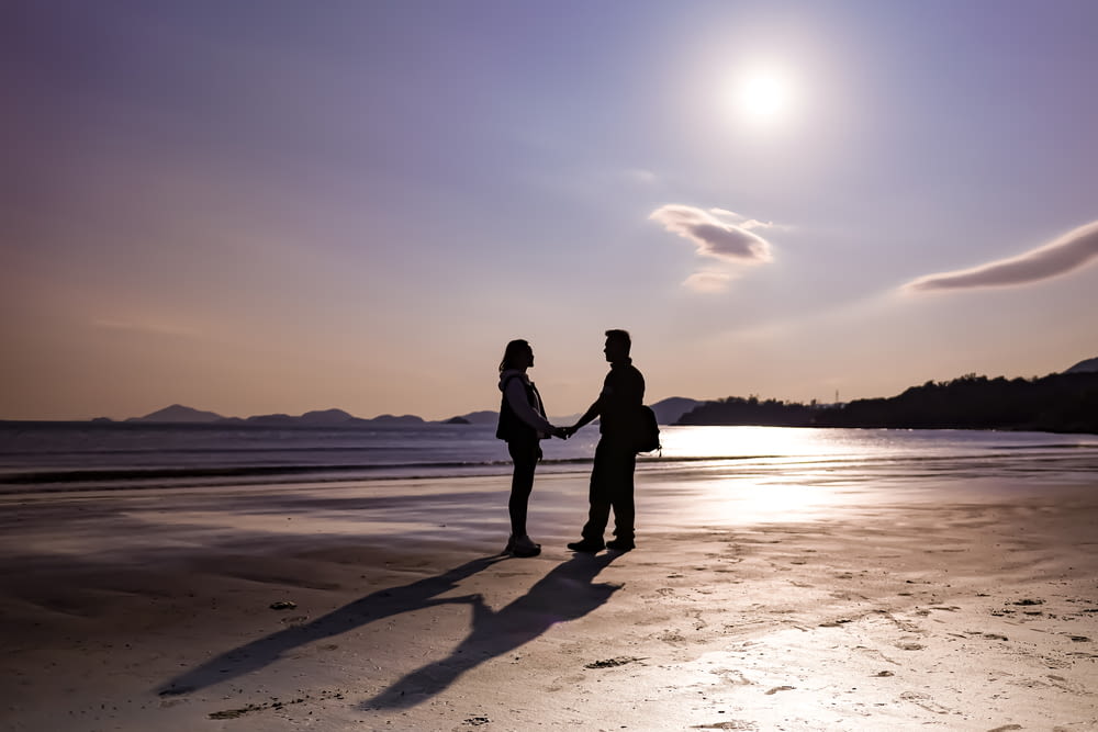 a man and a woman standing on a beach holding hands