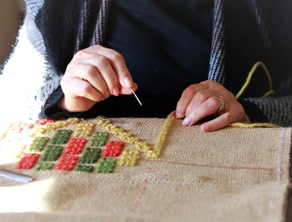 a woman is working on a cross stitch project