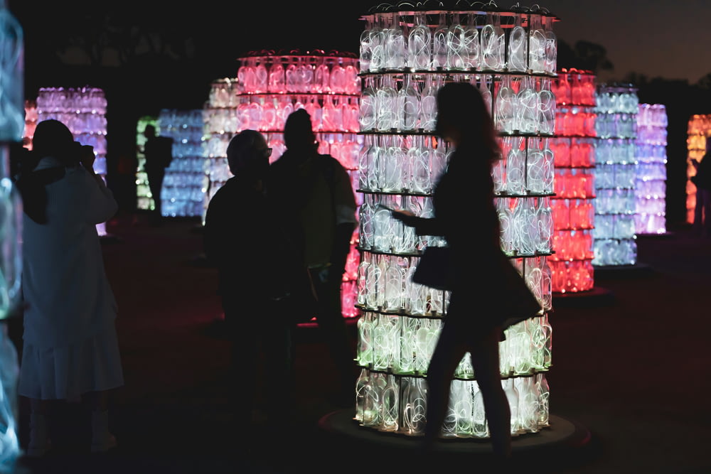 a group of people standing around a tower made of bottles
