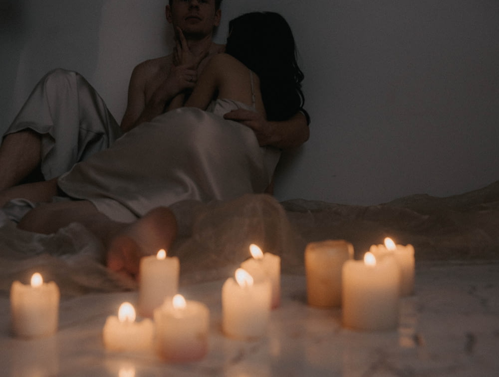 a man and a woman laying in bed with candles