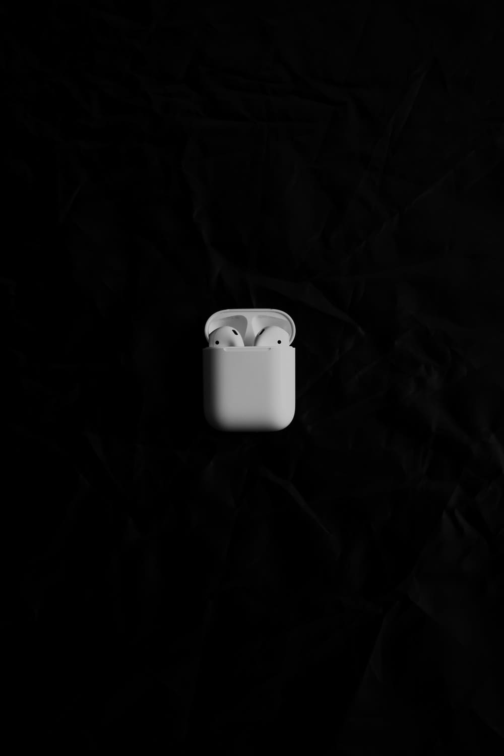 Ein weißer Apfel AirPods sitzt auf einer schwarzen Oberfläche