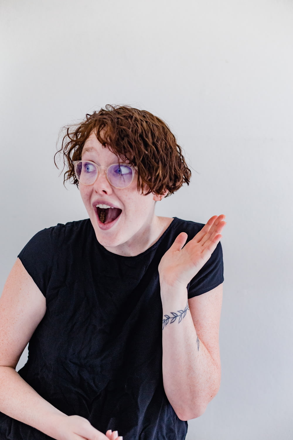 a woman with curly hair and glasses making a funny face