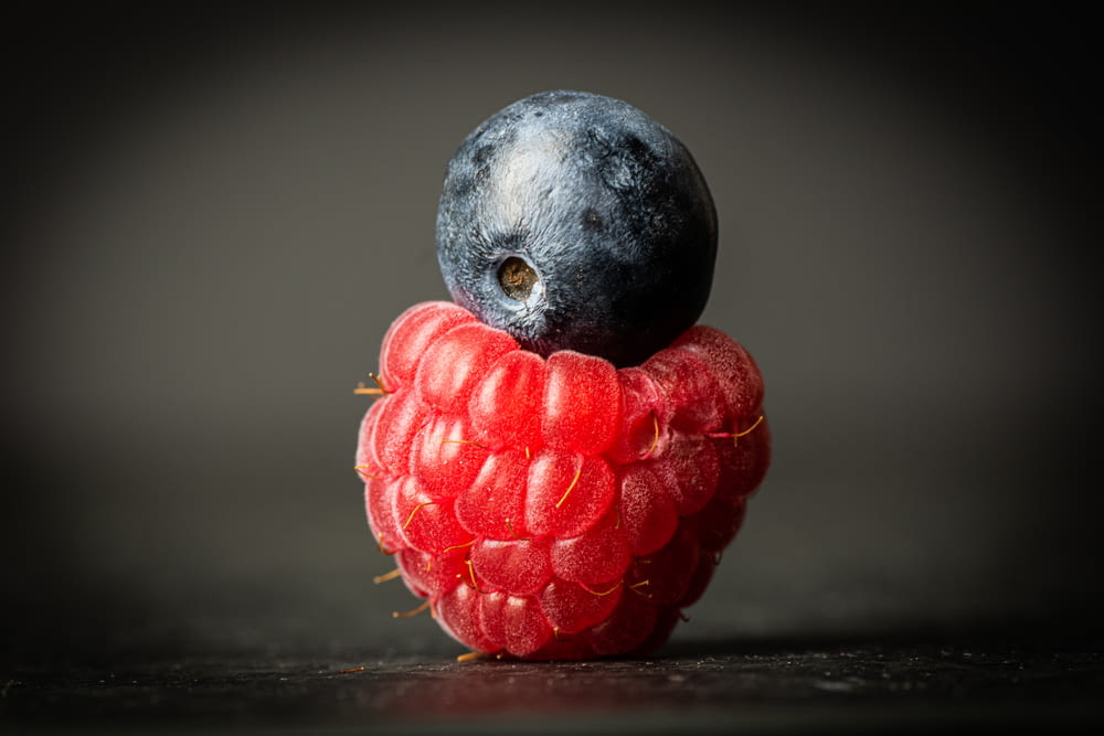 a blue bird sitting on top of a raspberry
