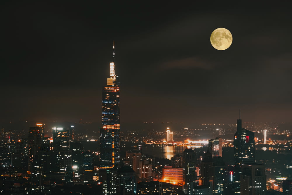 a view of a city at night with a full moon