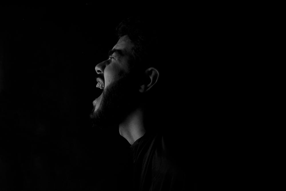 Un homme avec une barbe debout dans le noir