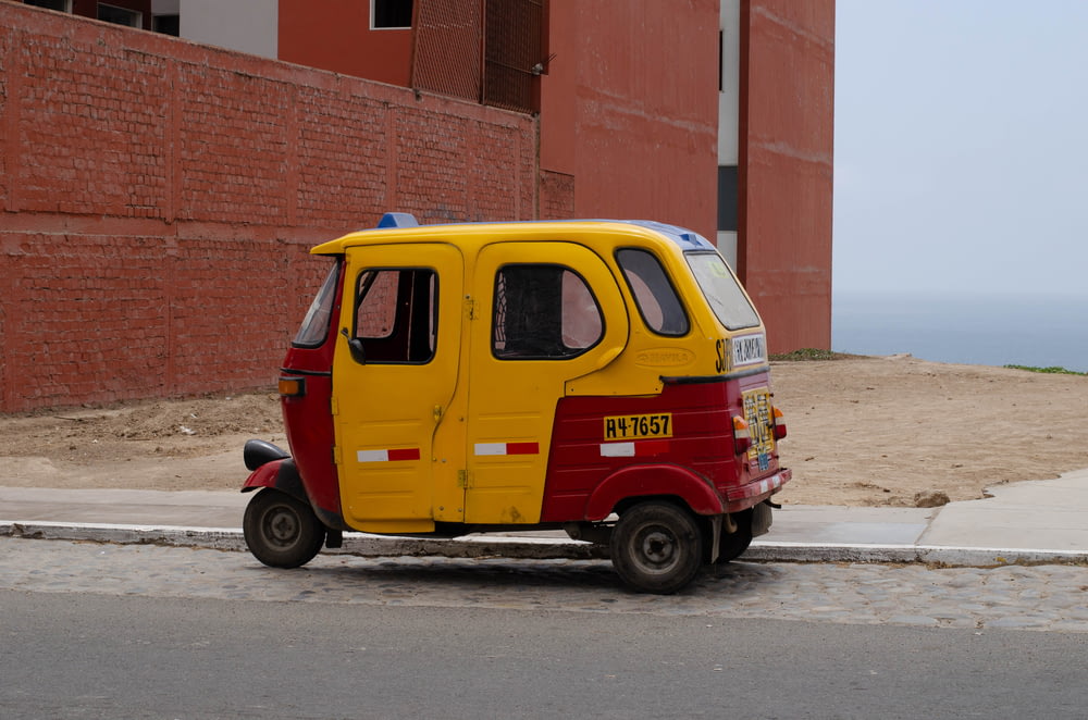 a small yellow and red vehicle parked on the side of a road