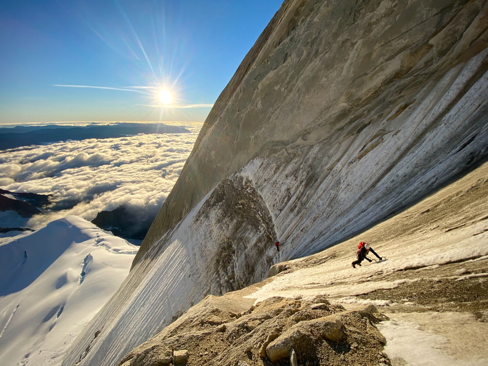 um homem subindo o lado de uma montanha coberta de neve
