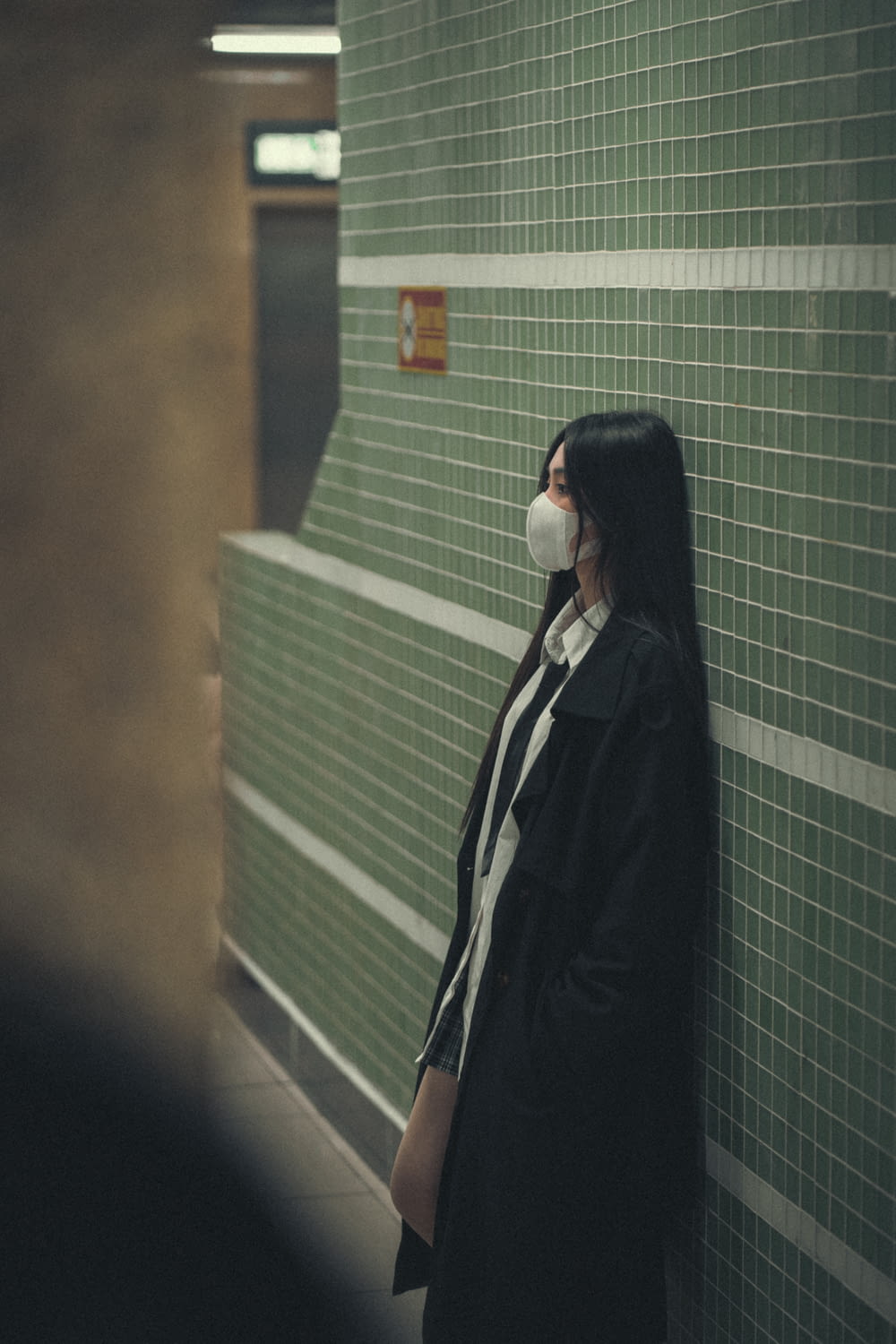 una donna che indossa una maschera facciale in piedi contro un muro