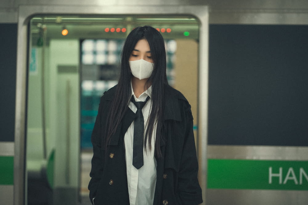 una donna che indossa una maschera in piedi davanti a un treno