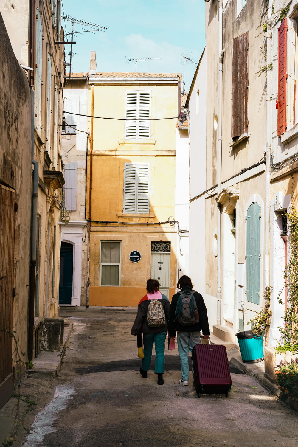 a couple of people walking down a street with luggage